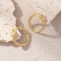 Macro view of gold hoop earrings with butterfly accent and micro-pave crystals - Butterfly Decor Hoop