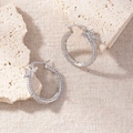 Detailed macro view of silver butterfly hoop earrings with sparkling cubic zirconia pavé - Butterfly Edge Pave