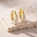 Detail of elegant gold hoop earrings with three rows of white pearls on stone background - Retro Triple Row Pearl Hoop