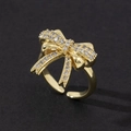 Bague nœud dorée ajustable sertie de zircones cubiques sur un fond noir mat - Style de Noeud Brillant en 3D Doré (F)
