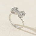 Gros plan sur bague nœud argentée sertie de zircons sur un fond crème texturé élégant - Style de Noeud Poli Miroir en Argent (I)