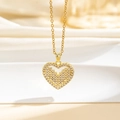Dettaglio del ciondolo a cuore dorato con zirconi e trama a croce su sfondo di seta - Texture a Croce Oro (Q)