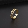 Dettaglio di anello multistrato dorato con micro-pavè di zirconi e design a treccia - Croce d'Oro a Triplo Strato (K)