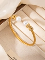 Dettaglio di un bracciale a treccia dorata con grandi perle e piccoli cristalli luminosi - Oro