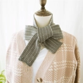 Grey and green polka dot knitted scarf tied in a bow on a mannequin display - Gray