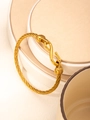Dettaglio di un bracciale a cavo dorato con trama a spirale e chiusura a gancio a S - Oro