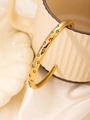 Detail eines goldenen Armreifs mit Sterngravur und Zirkonia an einer Tasse - Gold