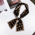 Elegant black silk twilly scarf with orange heart patterns and tan borders on a desk - Black Heart