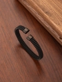 Detail of black stainless steel mesh woven cuff bracelet on a wooden surface - 18K Gold / Black
