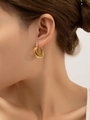 Gros plan de boucles d'oreilles dorées en C avec texture martelée portées par un modèle - Boucle d'Oreille à Texture de Lave Martelée Dorée (eh032)