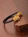 Macro shot of 18k gold dragon heads with detailed scales on black steel wire rope bracelet - Gold & Black