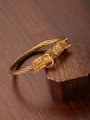 Detailed close-up of a 18k gold plated dragon head cable bracelet on a wooden display - Gold