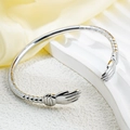 Minimalist silver hug hand cuff bracelet with sunburst texture on a premium display stand - Steel