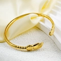 Macro detail of gold-plated embrace hands bangle featuring intricate floral texture and C-shape - Gold