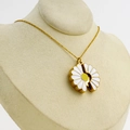 Elegant 18k gold plated daisy necklace with white enamel petals on a jewelry display - Gold