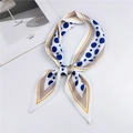 Sciarpa di seta beige a pois blu annodata a fiocco su uno sfondo bianco - Blu