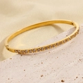 Elegant gold titanium steel hinged bangle with inset crystals on a silk backdrop - Triangle Notch Zirconia Style (ztx078)