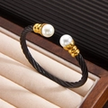 Close-up of twisted black steel cable bracelet with 18k gold caps and white pearls - Black Gold Bangle