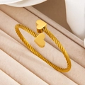 Minimalist 18k gold plated twisted heart bangle on a soft beige velvet jewelry display - 136 Gold