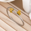 Twisted steel rope bracelet with golden heart charms on beige velvet display - 136 Two-tone