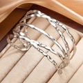 Bracciale rigido moderno in argento S925 con linee ondulate su una scatola di gioielli - Color Acciaio