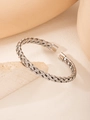 Dettaglio ravvicinato di un bracciale rigido a treccia argento su oggetti minimalisti - Color Acciaio
