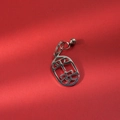 Close-up of silver hollowed Ping An charm with a small bell on festive red background - Safety and Peace