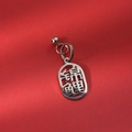 Macro shot of a silver stainless steel Koi fish charm with a small bell on a red surface - Koi Fish