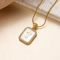 Goldene Kette mit Buchstabe T Anhänger aus Muschel und Kristallen auf Seidenhintergrund - Buchstabe T