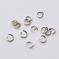 Macro view of scattered stainless steel jump rings for jewelry making on a white surface - 0.8x4mm / Original Stainless Steel