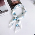 Elegant white silk square scarf with blue swan pattern knot displayed on table - Blue Swan