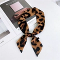 Classic leopard print silk twilly scarf tied on a magazine, showing its glossy brown pattern - Amur Leopard Yellow