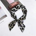 Petit foulard en soie étroit à imprimé léopard gris et noir noué sur une surface blanche - Léopard Gris