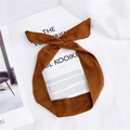 Bandeau à nœud en daim marron caramel avec fil interne réglable posé sur un magazine - Marron