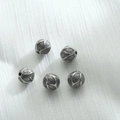 Primo piano di cinque perline distanziatrici vintage in acciaio inox con motivi a rilievo - Nero Acciaio