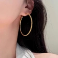 Detail of large gold hoop earrings featuring a twisted rope texture worn by a model - 5cm / Gold
