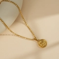 Gold Aquarius constellation pendant necklace with a Figaro chain on a beige base - Aquarius