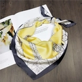Dettaglio di un foulard in seta con motivi geometrici su una rivista su fondo legno - 70cm / Torre Giallo