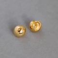 Macro detail of polished 18K gold-plated spherical earrings on a grey matte surface - Gold