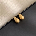 Primer plano de pendientes de gota dorados con textura de metal cepillado sobre negro - Estilo Cepillado (F110) / Dorado