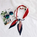 Close-up of a red and blue striped silk twilly scarf styled with chic sunglasses - Red Varied Stripes