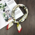 Close-up of a printed silk neck scarf with artistic patterns on a dark wooden background - 60x60cm / Palm Pattern Cream Yellow