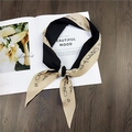 Close-up of diamond-shaped silk scarf featuring black khaki patchwork and cursive prints - Black Letter Print