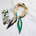 Dettaglio di un foulard in seta a fiori verdi e rossi su sfondo di tessuto bianco piegato - Fiori Verdi
