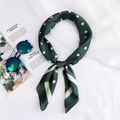 Close-up of a green polka dot silk scarf tied in a stylish loop on a fashion magazine - Green