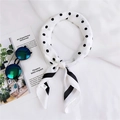Gros plan d'un foulard en soie blanc à pois noirs et bord rayé sur un fond en tissu blanc - Blanc