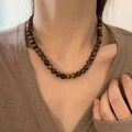 Tijgeroog kralenketting met natuurlijke bruine texturen gedragen door een model - 10mm Tijgeroog Ketting