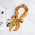 Close-up of bright yellow satin scarf tied in a bow on a white textured fabric background - Yellow