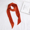 Close-up of orange satin twilly scarf on white linen next to a minimalist lifestyle magazine - Orange