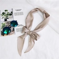 Elegant champagne satin skinny scarf tied in a bow on a stylish textured background - Gray